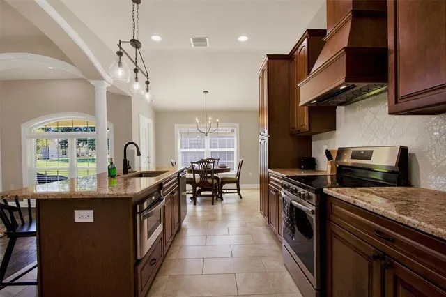 a kitchen with stainless steel appliances granite countertop a sink a stove and a wooden floors