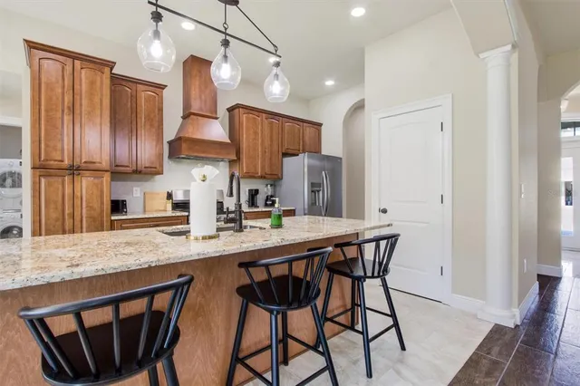 a kitchen with stainless steel appliances granite countertop a sink a stove a refrigerator cabinets and wooden floor