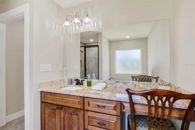 a bathroom with a granite countertop sink a light fixture and a mirror