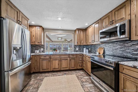 a kitchen with stainless steel appliances granite countertop a refrigerator and a stove top oven