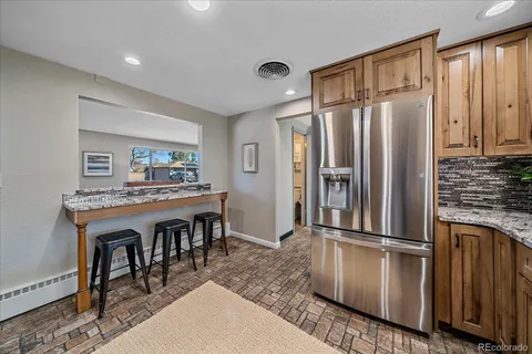 a kitchen with stainless steel appliances granite countertop a refrigerator a stove and a sink with wooden floor
