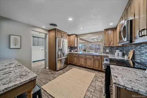 a kitchen with granite countertop a refrigerator a stove and wooden cabinets