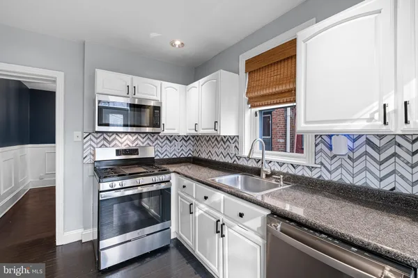 a kitchen with granite countertop a sink stove and microwave