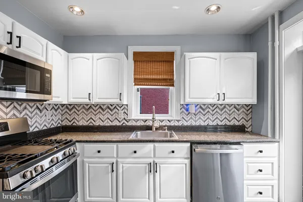 a kitchen with granite countertop a sink a stove and cabinets