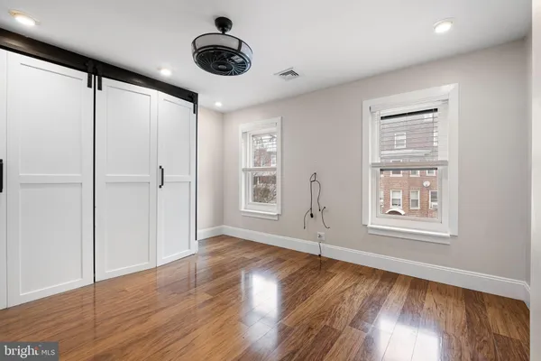 an empty room with wooden floor and windows