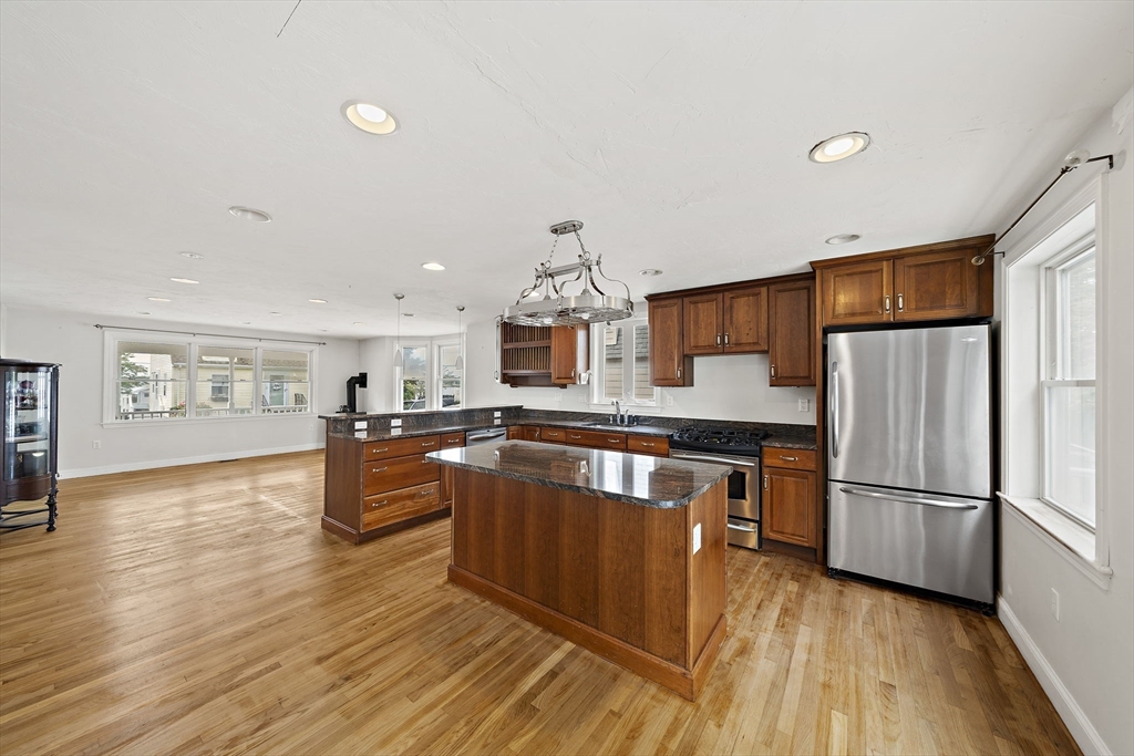 92 Spring Street Quincy, MA 02169 - Photo 7 of 34 a kitchen with granite countertop a refrigerator a stove top oven and a dining table with wooden floor