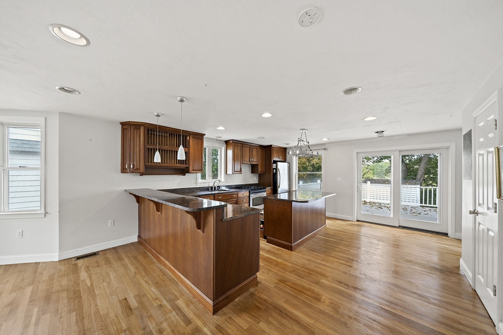 92 Spring Street Quincy, MA 02169 - Photo 8 of 34 a kitchen with stainless steel appliances granite countertop a stove top oven a sink dishwasher and a refrigerator with wooden floor
