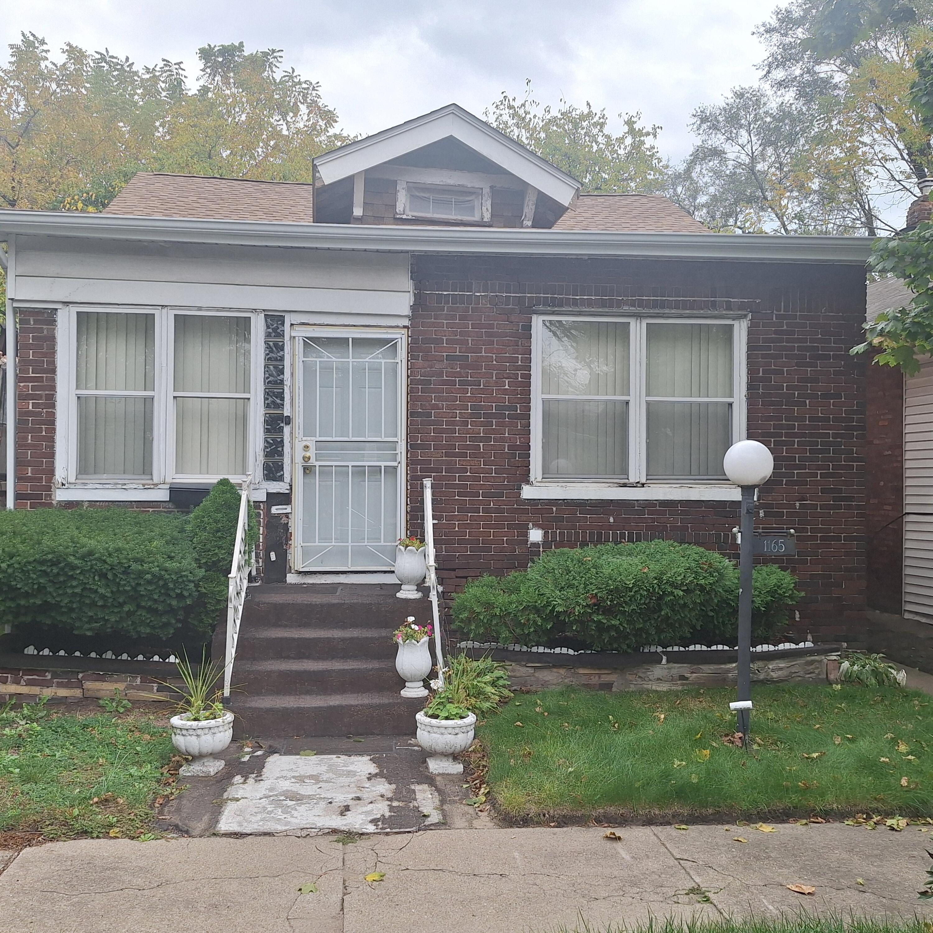 a front view of a house with a yard and potted plants