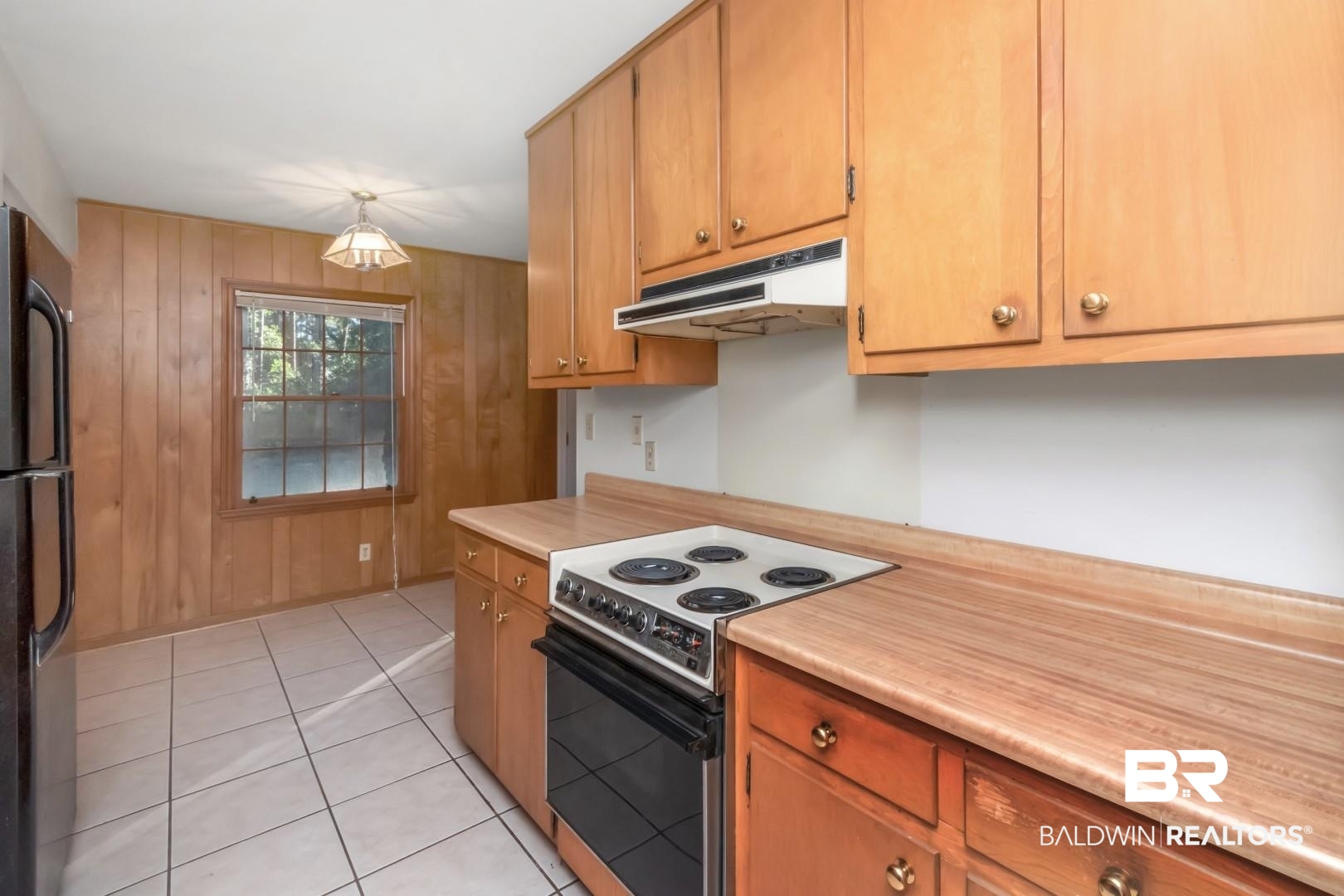 5517 Vanderbilt Drive Mobile, AL 36608 - Photo 21 of 33 Kitchen featuring pendant lighting, black fridge, wooden walls, electric range, and light tile patterned floors