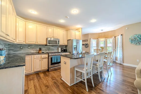 a kitchen with stainless steel appliances granite countertop wooden floor a stove a sink dishwasher and a refrigerator