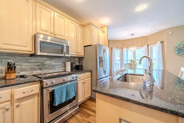 a kitchen with stainless steel appliances granite countertop a sink a stove and a refrigerator