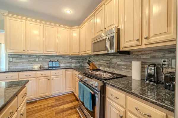 a kitchen with stainless steel appliances granite countertop a sink a stove and cabinets