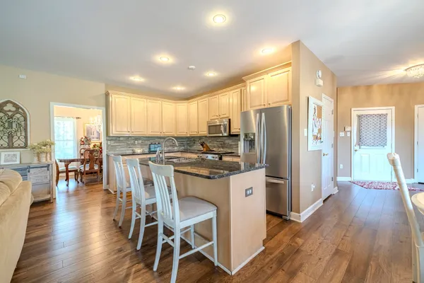 a kitchen with stainless steel appliances a refrigerator a stove top oven and a dining table with wooden floor