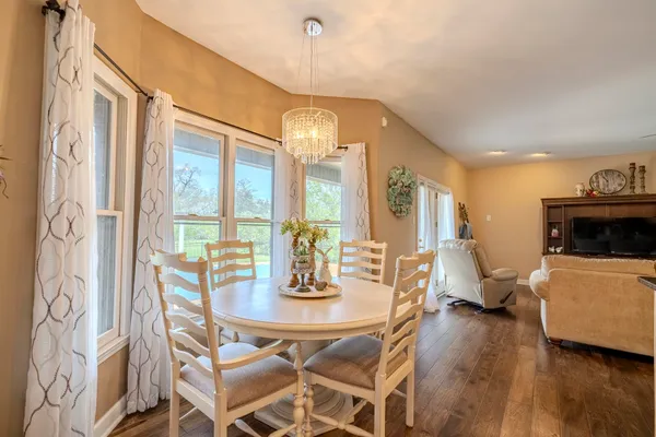 a dining room with wooden floor a chandelier a glass table and chairs