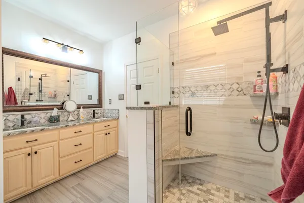 a bathroom with a granite countertop sink a shower and a mirror