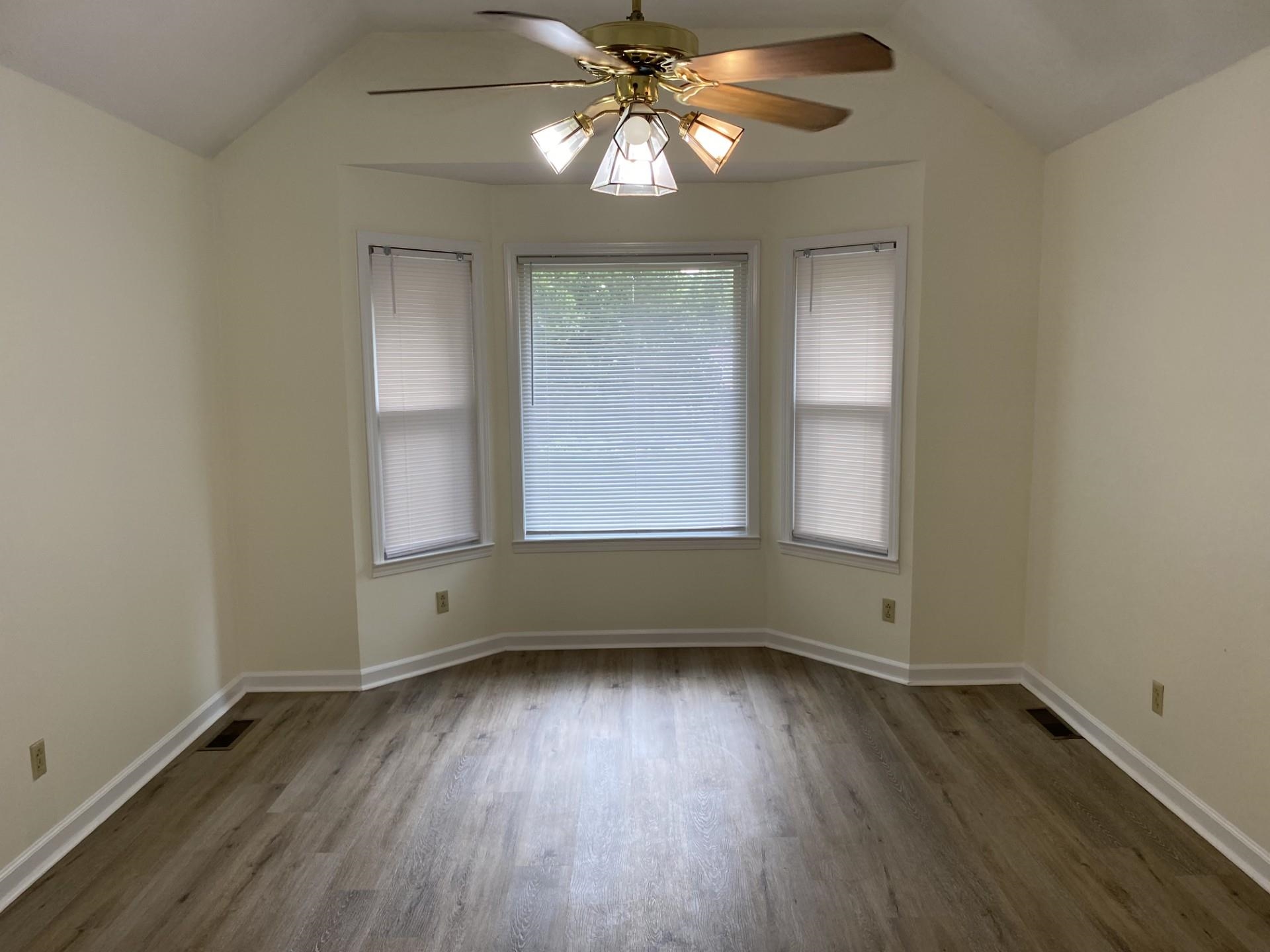 81 Candlewick Drive Jackson, TN 38305 - Photo 11 of 30 an empty room with wooden floor chandelier fan and windows