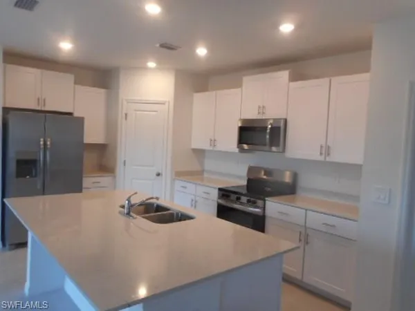 a kitchen with kitchen island a counter space a sink and stainless steel appliances