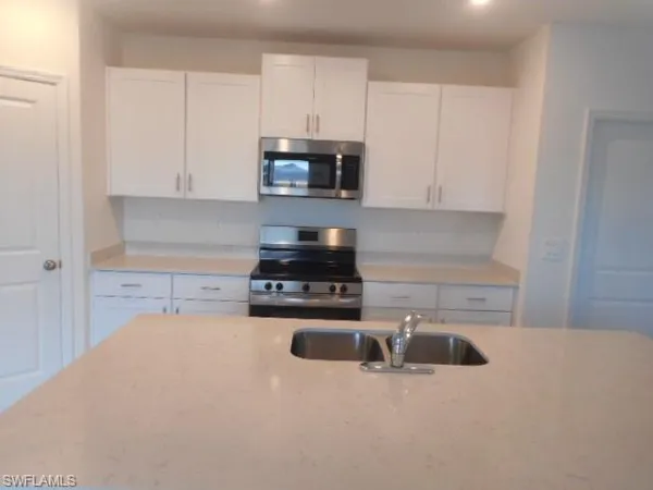 a kitchen with granite countertop a sink a stove and cabinets