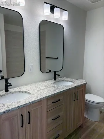 a bathroom with a granite countertop toilet sink and mirror