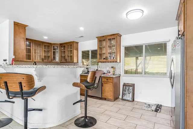 a view of a kitchen with kitchen island granite countertop a refrigerator and a sink