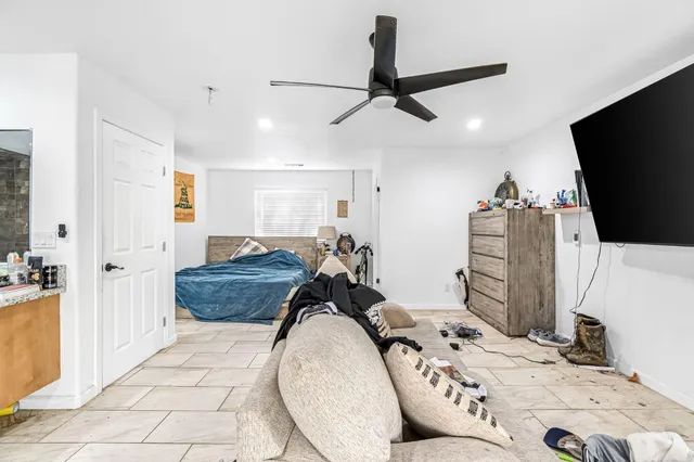 a living room with furniture a flat screen tv and a refrigerator