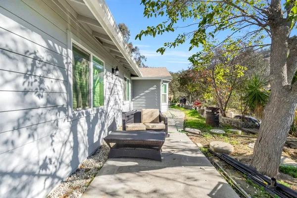 a view of a patio with couches table and chairs with wooden fence and large trees
