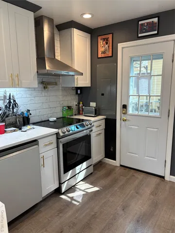 a kitchen with stainless steel appliances white cabinets and a stove top oven