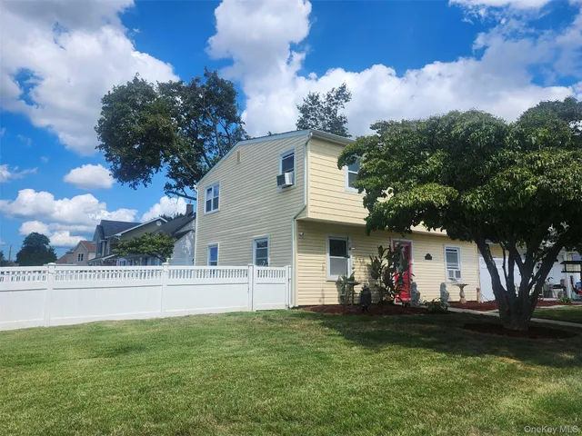 a view of a white house with a back yard and a garden