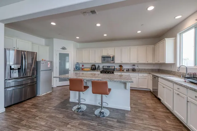 a kitchen with kitchen island white cabinets and stainless steel appliances