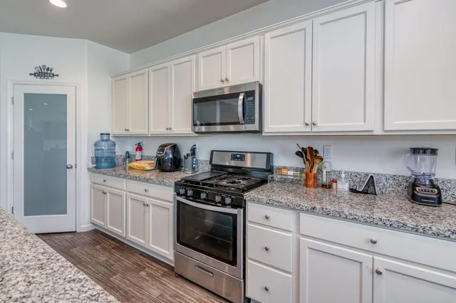 a kitchen with granite countertop white cabinets and stainless steel appliances