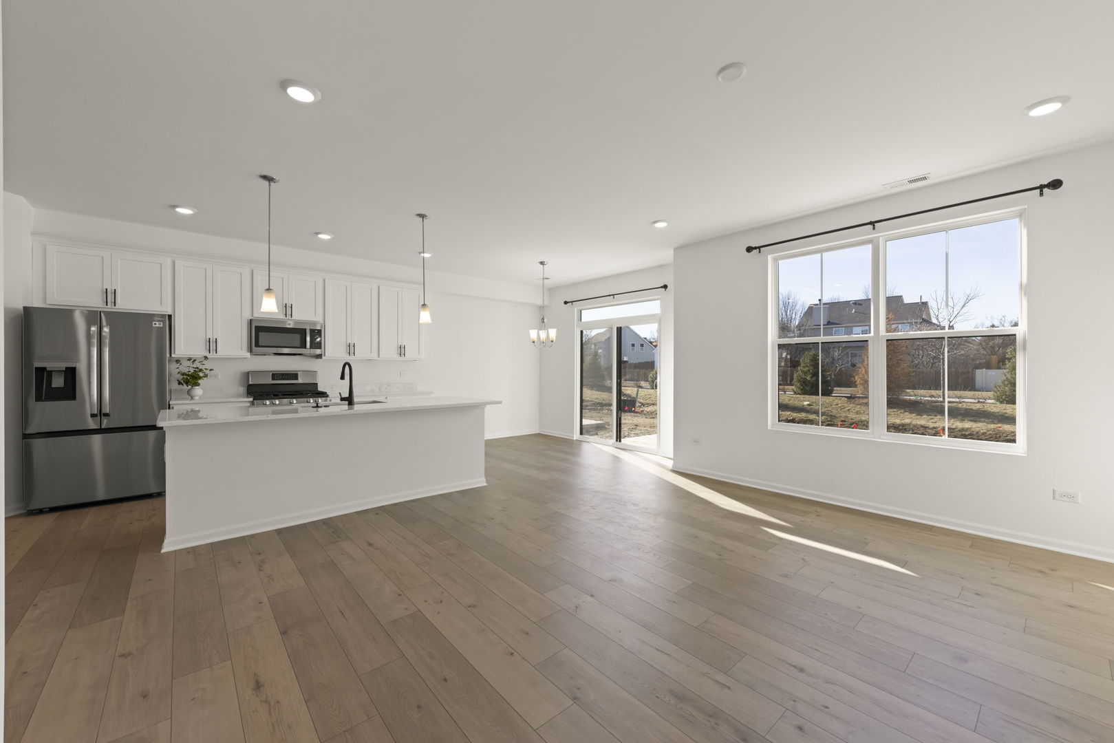 4486 Chelsea Mnr Circle Aurora, IL 60504 - Photo 7 of 23 a large kitchen with stainless steel appliances kitchen island granite countertop a stove a refrigerator a sink a microwave and white cabinets with wooden floor next to windows