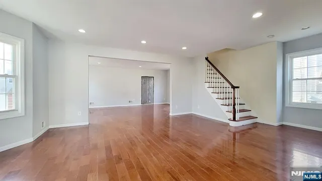 a view of an empty room with wooden floor and windows