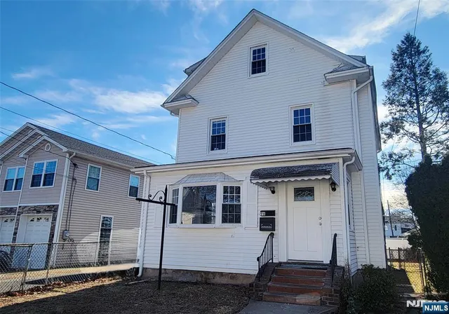 a view of a white house with wooden fence and large windows