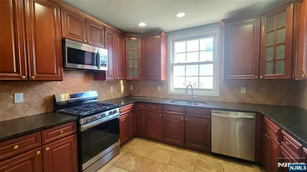 a kitchen with stainless steel appliances granite countertop wooden cabinets a stove top oven a sink and dishwasher