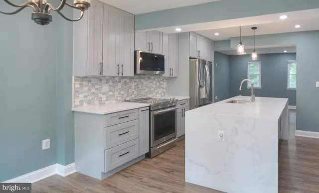 a kitchen with kitchen island white cabinets and stainless steel appliances