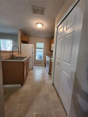 a view of a kitchen with fridge and wooden floor