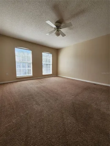 an empty room with windows and ceiling fan