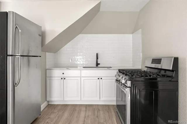 a kitchen with white cabinets and refrigerator