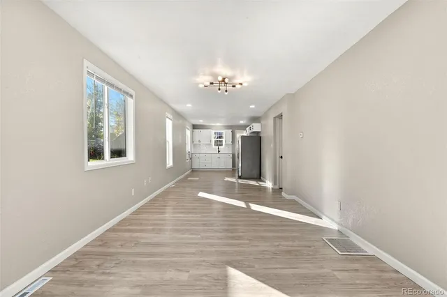 a view of an empty room with window and wooden floor