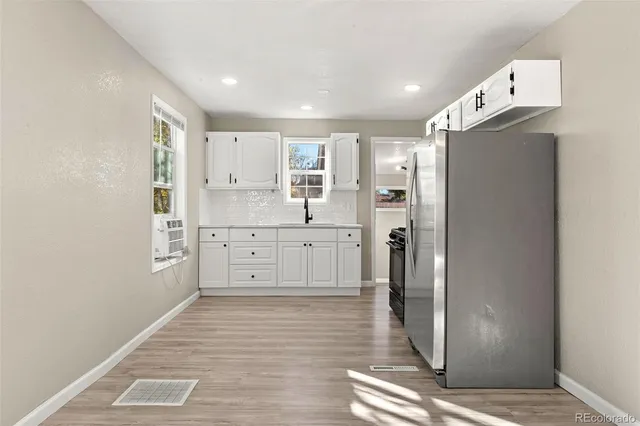 a view of a kitchen with refrigerator and wooden floor