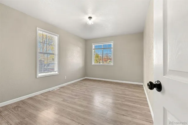 a view of an empty room with a window and wooden floor