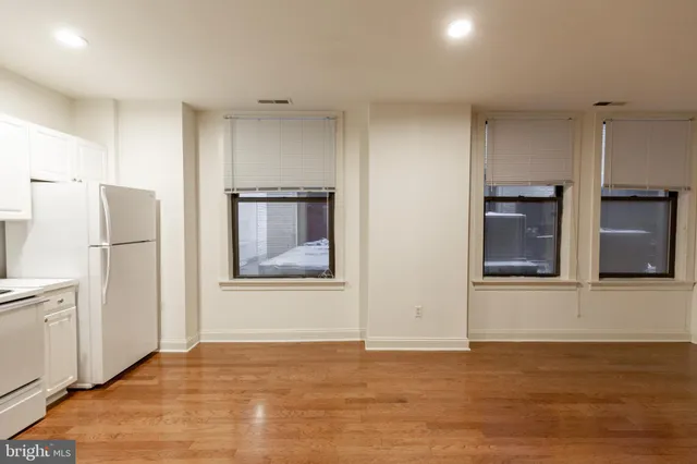 a view of an empty room with a kitchen and a window