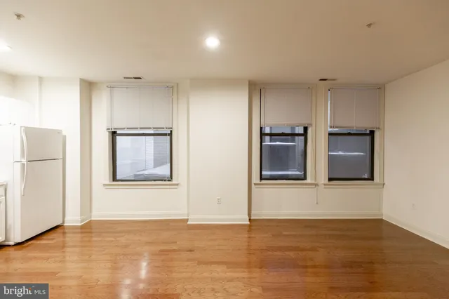 a view of an empty room with a kitchen and wooden floor
