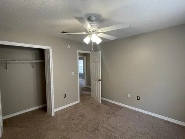 an empty room with closet and a chandelier fan