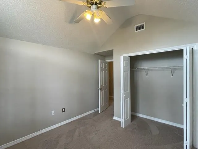 an empty room with closet and a chandelier fan