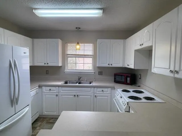 a kitchen with a sink a stove a refrigerator and cabinets