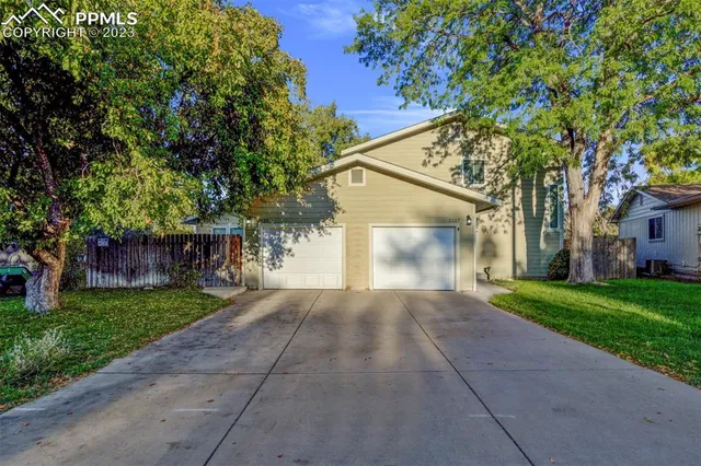 front view of a house with a yard and an trees