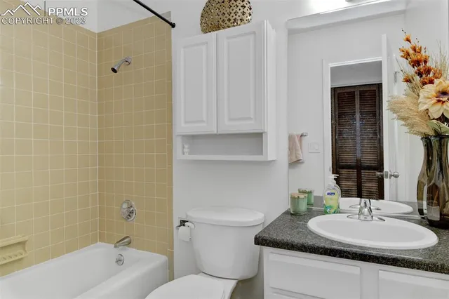 a bathroom with a granite countertop sink a toilet a mirror and shower