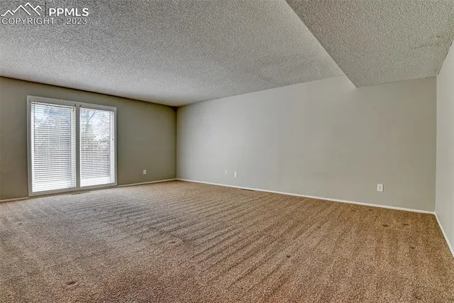 a view of an empty room with a window and a kitchen