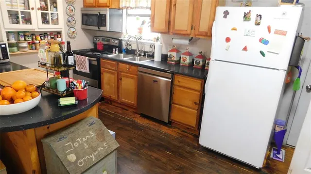 a kitchen with stainless steel appliances a refrigerator sink and wooden floor